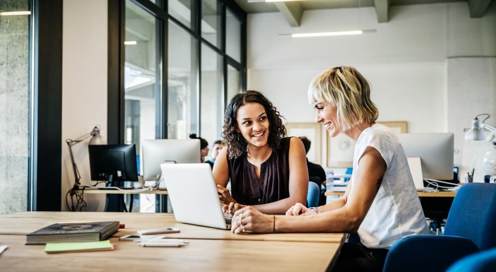 Two business women sharing ideas over a laptop.